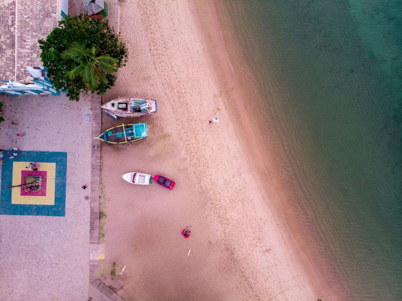 Imagem da beira-mar de uma praia com alguns barcos