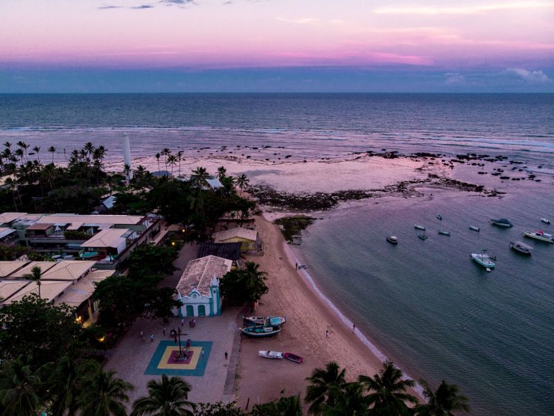 Imagem de uma praia com barcos na areia e no mar