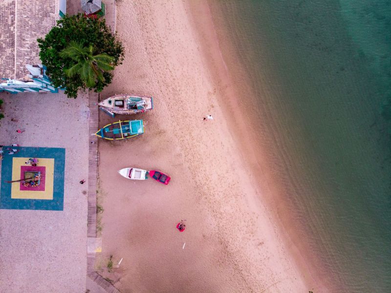 Imagem aérea de uma praia com alguns barcos na areia