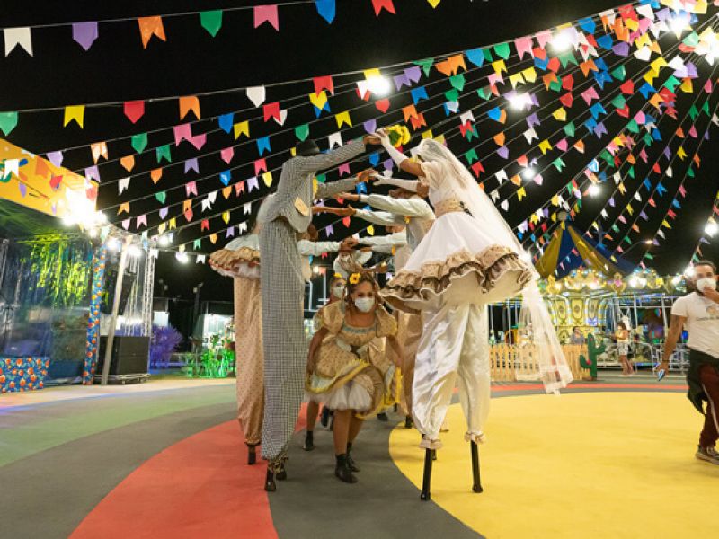 Imagem de uma festa de São na Bahia. Nela, as pessoas estão dançando a quadrilha próximas as bandeirinhas.