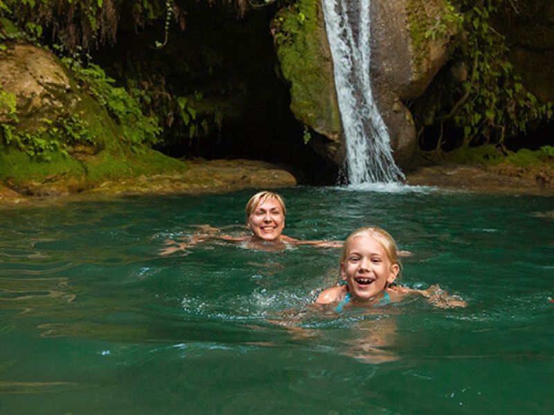 Imagem de uma mulher e uma criança nadando em uma cachoeira