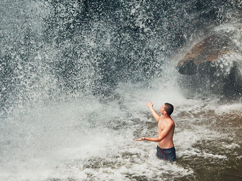 Imagem de um homem embaixo de uma cachoeira