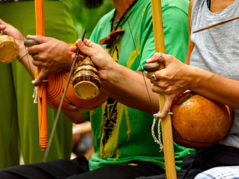 Pessoas que tocam berimbau em uma tradicional roda de capoeira