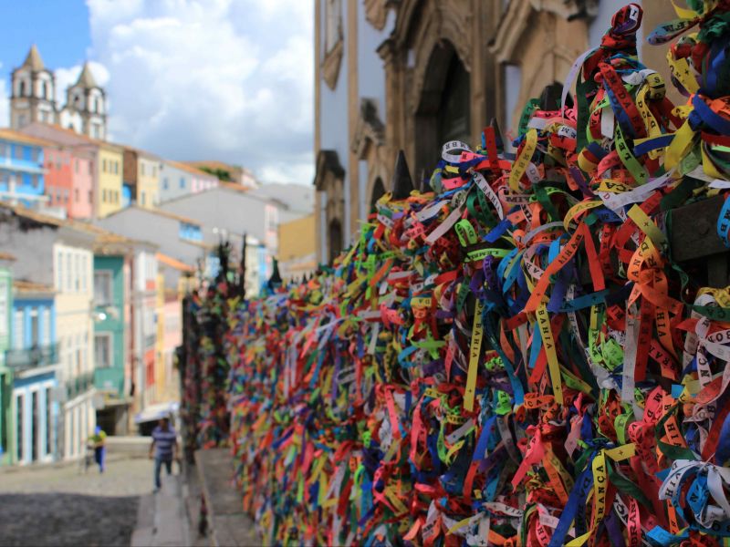 Rua no Pelourinho, em Salvador, com fitinhas de Bonfim amarradas em um portão lateral 