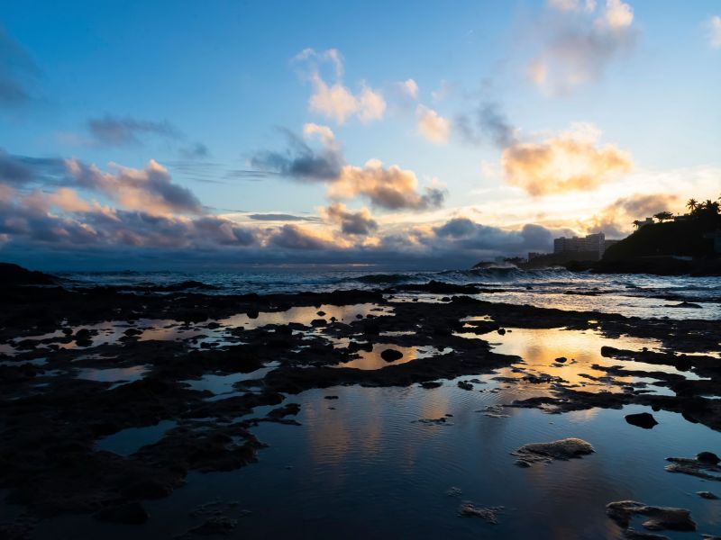 Orla da Praia de Ondina, em Salvador. O sol está se pondo no horizonte