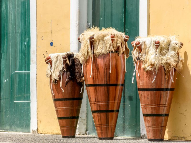 três atabaques do afoxé encostados em uma parede amarela com portas verdes