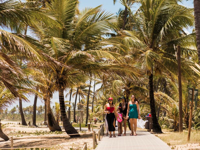 mulheres e uma criança caminhando pelo caminho de madeira que da acesso à praia da Costa do Sauípe Resorts