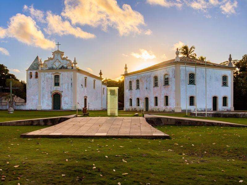 Museu histórico de Porto Seguro e a Igreja Nossa Senhora da Penha. Dois prédios antigos com o pôr do sol ao fundo
