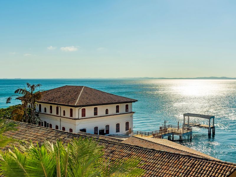 Solar do unhão, na Bahia. Prédio branco em estilo colonial na beira do mar cristalino.