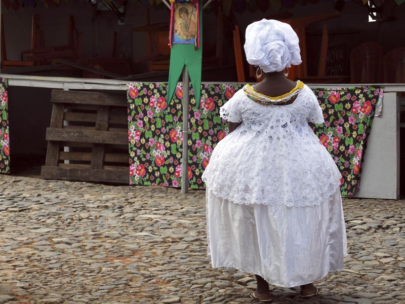 Mulher vestindo as tradições roupas de baiana, de costas para a câmera 