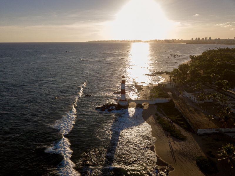 Pôr do sol com o farol no mar de Salvador, na região de Itapuã