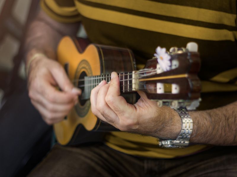 Parte do corpo e mão de um homem tocando um cavaquinho