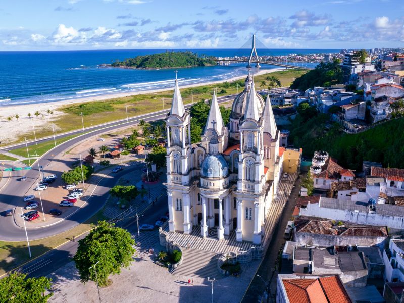 Igreja de Ilhéus com o mar do lado esquerdo e os prédios da cidade na direita