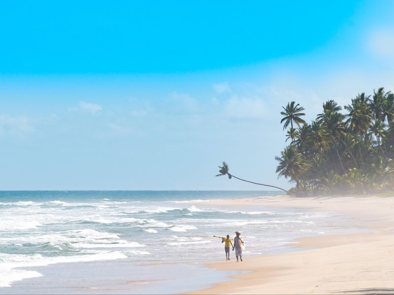 Duas pessoas caminhando pela orla da Praia de Itacaré